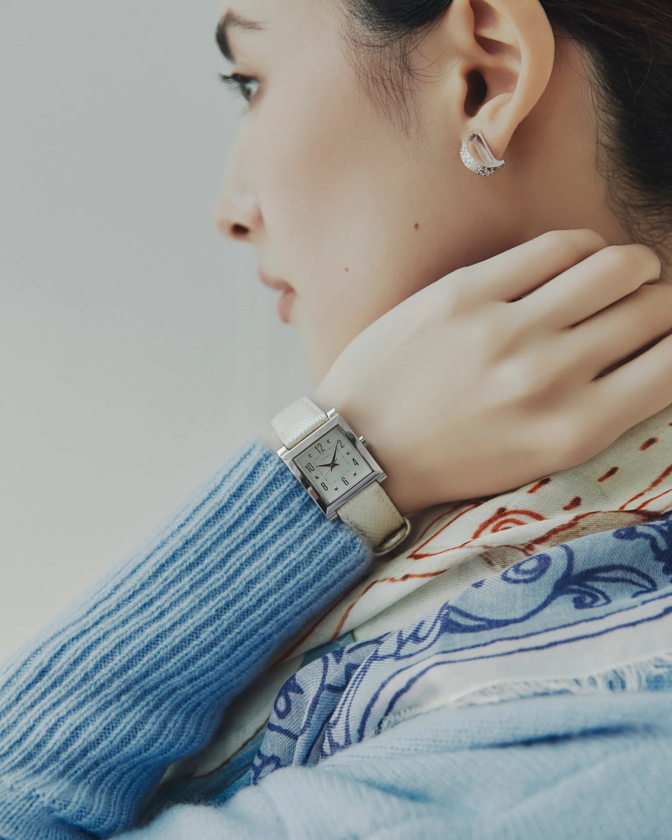 モデルに近づくことで、耳に付けられたリロ ピアス〈スズランプレート・S〉と手首に付けられたWAKOウオッチ〈婦人用〉 パール加工がはっきりと写っている様子