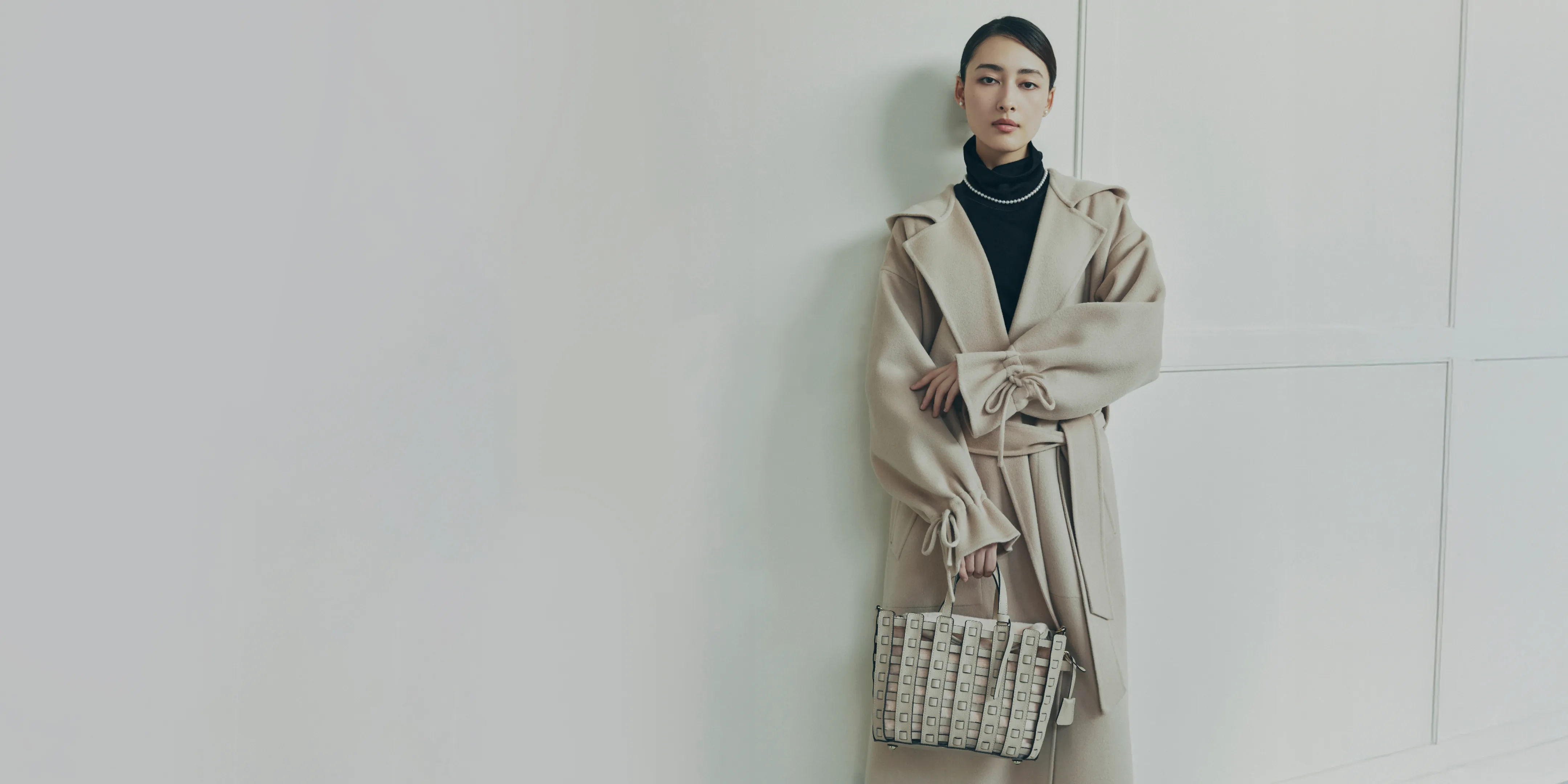 NEW CLOSET リバーフードコートを着用したモデルがmica della valleメッシュトートバッグを持ち綺麗な姿勢で立っている様子